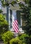 An American flag hanging in the front of a home in a neighborhood