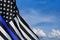American flag with police support symbol Thin blue line on blue cloudy sky.