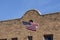 American flag waves from retro southwestern style brick building facade hung with party lights