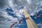 American flags blowing in the wind with the Washington Monument along the National Mall. Partly cloudy sky