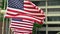 American Flags fly in slow motion in front of a typical small city backdrop