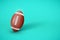 American Football ball on bright mint background