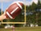 American Football in Hand over Field with Goal Post