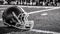 American football helmet laying in the grass black and white