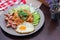 American fried rice served with fried sausage, cucumber, chopped vegetables in a gray plate on a brown wooden table with