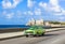American green 1952 vintage car on the promenade Malecon and in the background the Castillo de los Tres Reyes
