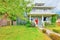 American green two level house exterior with white trim and red entrance door.