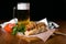 American Hotdogs with the glass of beer with sweet bubbles. Hotdogs and chips on table on dark background.