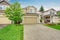 American house exterior with garage, driveway and well kept lawn.