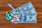 american hundred dollar bills with capsules and syringe on wood,