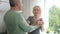 American husband giving gift to wife, hugs with smile in lighting room.