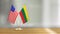 American and Lithuanian flag pair on a desk over defocused background