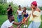 American male standing on one knee asking woman marriage giving ring proposing surprised shocked while gathering group