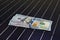 American money on solar panel surface. Renewable energy cost