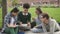 American multiracial four person talking, working using computer, sitting in park.