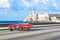 American red 1959 convertible vintage car on the promenade Malecon and in the background the Castillo de los Tres Reyes del Morro