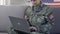 American servicewoman typing laptop and smiling on camera, searching information