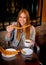 American student tourist girl sitting having spanish typical hot chocolate with churros smiling happy