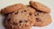 American style cookies with chocolate chips and raisins spin on a white table on a yellow background. Close up. prores