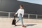 American trendy young man in stylish clothes in red sandals with a fabric bag in sunglasses is traveling on the street