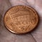 American US coin 1 cent penny lies on a dirty palm close up. An impressive, dramatic square shot with an aged effect. Low-wage