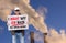 American worker with cap standing in front of industrials smoking chimneys with board sign saying I Want My Job Back Re-open Now.