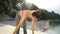 Amiable adult woman doing yoga by the sea