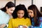 Amiable multiracial girls browsing social media using smartphone at home