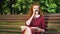 Amiable red haired reader relaxing in park