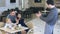 Amiable waiter take photo of friendly young family in cafe on smartphone.