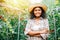 Amidst a tomato greenhouse a smiling woman farmer in checkered attire stands