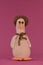 Amigurumi duck doll on pink background. Soft DIY toy made of cotton. One brown goose with orange beak wears hat and