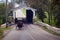 An Amish horse and buggy emerge from a covered bridge