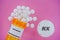 Amlodipine Rx medicine pills in plactic vial with tablets. Pills spilling from yellow container on pink background