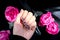 AMOR word on nails manicure hold Pink rose flower on black silk fabric. Minimal flat lay nature. Female hand. Love