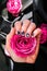 AMOR word on nails manicure hold Pink rose flower on black silk fabric. Minimal flat lay nature. Female hand. Love