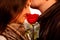 Amorous guy gently kissing his girl with red rose