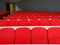 Amphitheater big lecture room with red chairs and white tables for students lined in rows for university or conference lectures