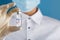 An ampoule with the inscription COVID-19 vaccine in the hands of a doctor-scientist in rubber gloves with a vaccine