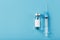 Ampoule with a vaccine and a syringe for viruses and diseases on a blue background