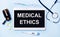 Ampoules, pills, stethoscope, thermometer, tablet with MEDICAL ETHICS text on desktop.