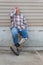 Amputee man sitting on stool with prosthetic leg crossed, looking up with hand to side of face