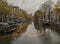 Amsterdam in autumn, waters of the canal and trees with yellow leaves.