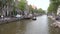 Amsterdam canal with boats, people walking along the embankment.