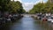 Amsterdam canal with bridge, boats, cars and bikes.