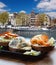 Amsterdam city with fishplate salomon and codfish sandwiches against tourboat on canal in Netherlands