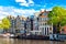 Amsterdam cityscape view of the canal in summer with blue sky, houseboat and traditional old houses. Picturesque of Amsterdam, The
