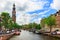 Amsterdam, Netherlands - August 3, 2017: Traditional holland houses, Westerkerk church, boats and people on Prinsengracht canal.