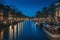 Amsterdam night city skyline at water canal waterfront with boat houses, Amsterdam, Netherlands