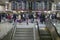 Amtrak train travelers stand in line under Departures sign, while a man goes down escalator at Penn Station, New York City